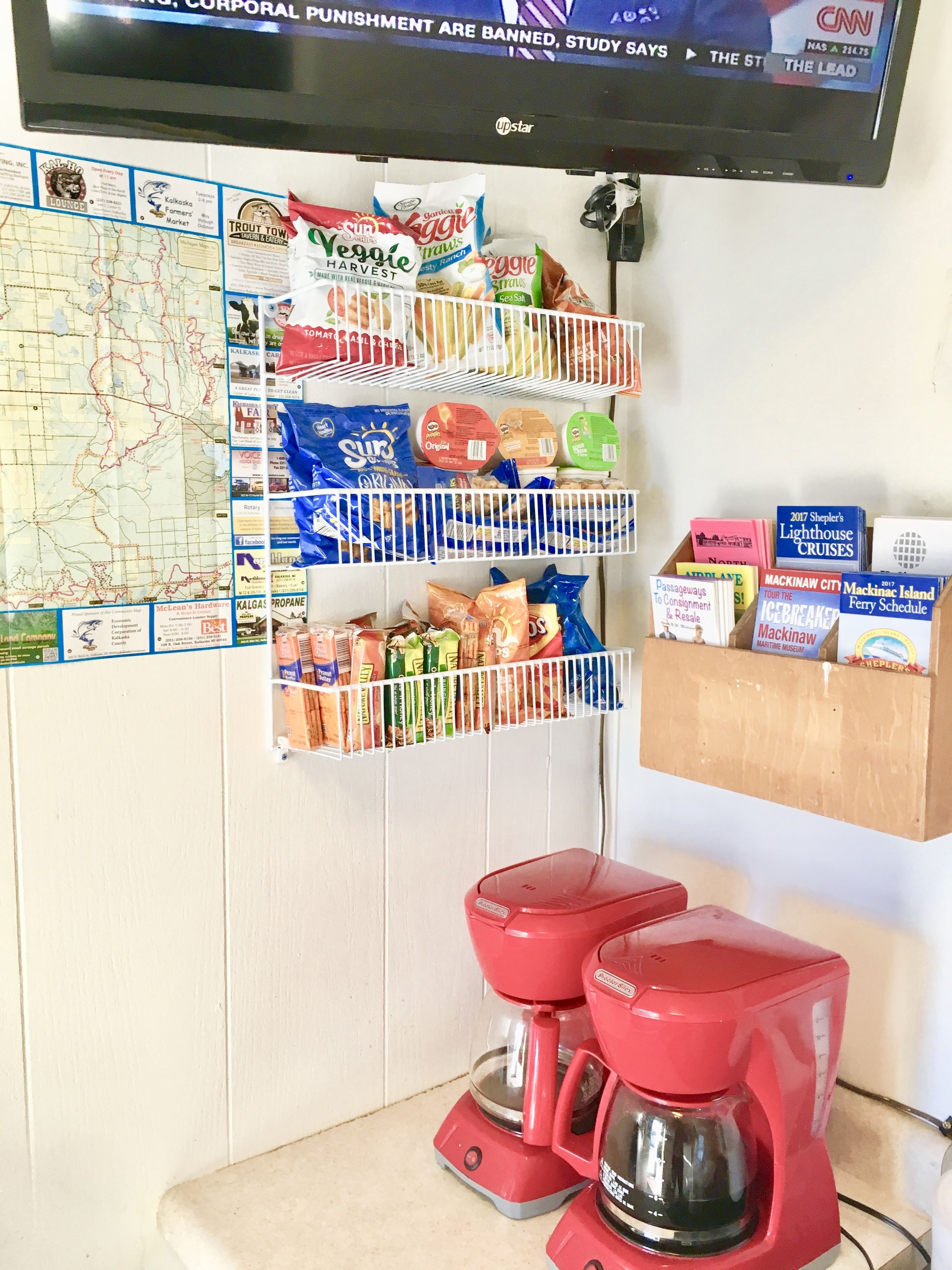 A kitchen area with a coffee maker, a map, and various food items on shelves.