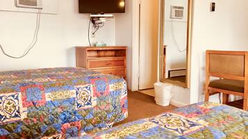 A hotel room with two beds, a wooden dresser, a television, a mirror, and a chair.