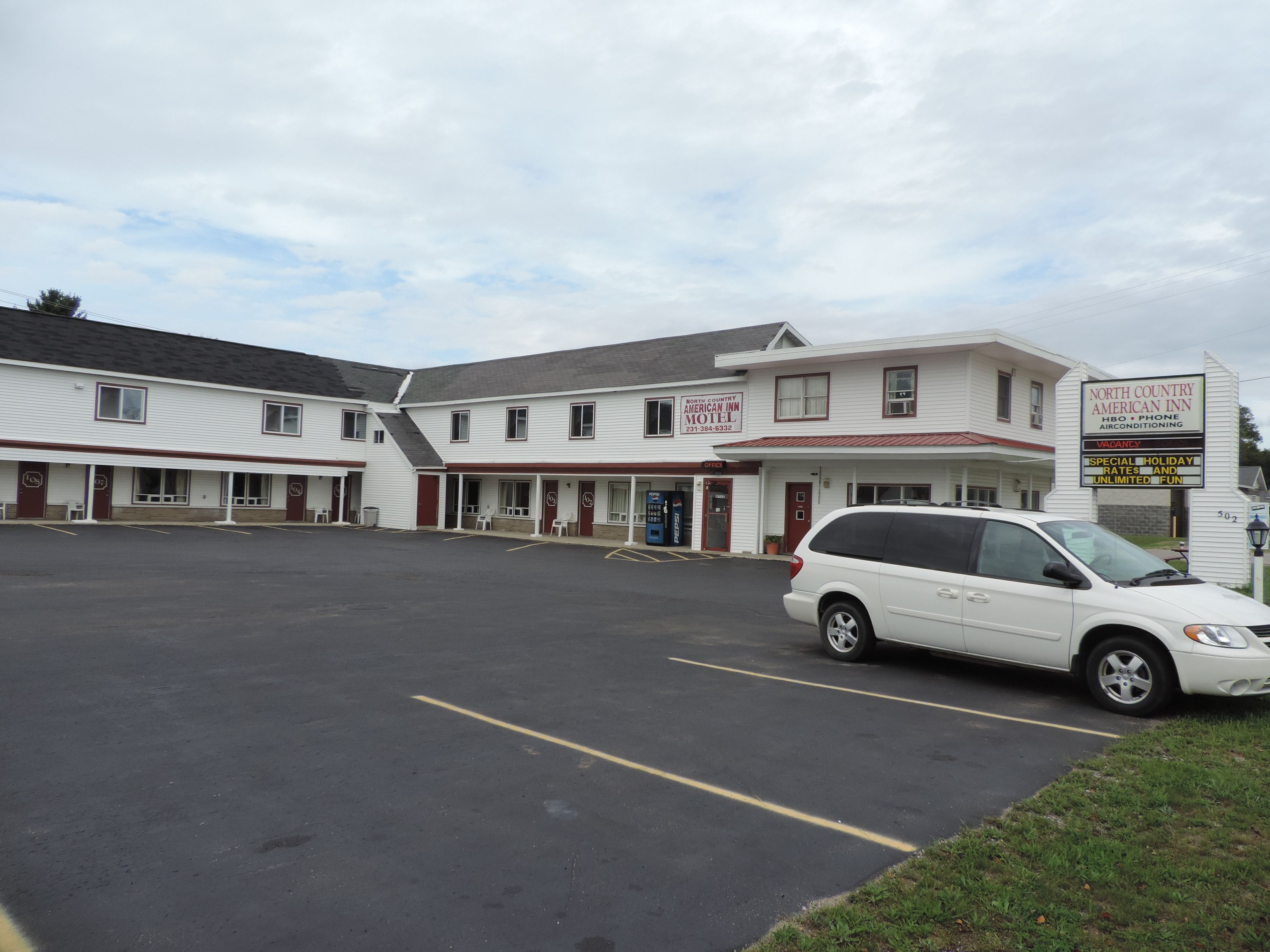 A motel with multiple units, a parking lot, and a white SUV parked in front.