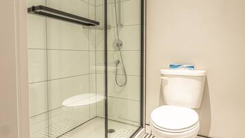 Un baño moderno con ducha envuelta en vidrio, inodoro blanco y baldosas de piso con diseño.