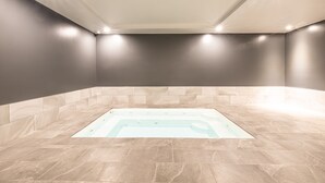 Un cuarto de spa con hidromasaje, luces empotradas y paredes de azulejos.