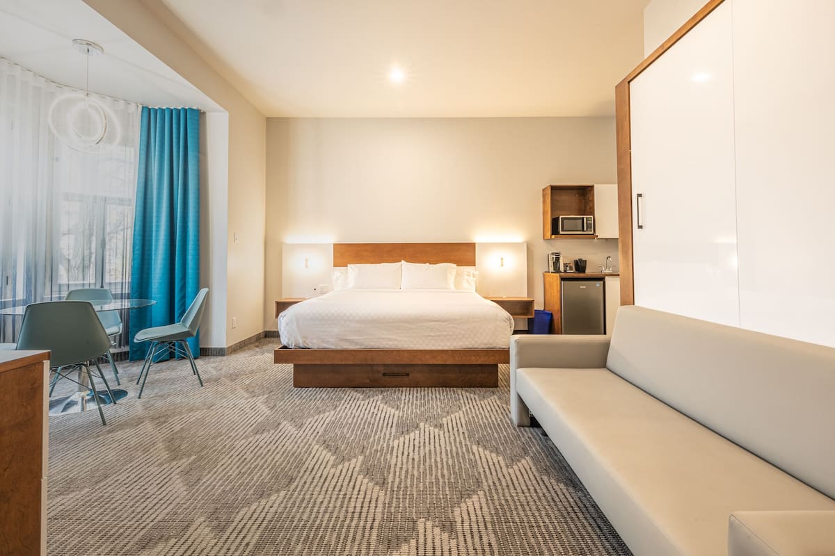 Ein Hotelzimmer mit einem Bett, Nachttischen, einem Sofa, einem Schreibtisch mit Stühlen und einer Mikrowelle.