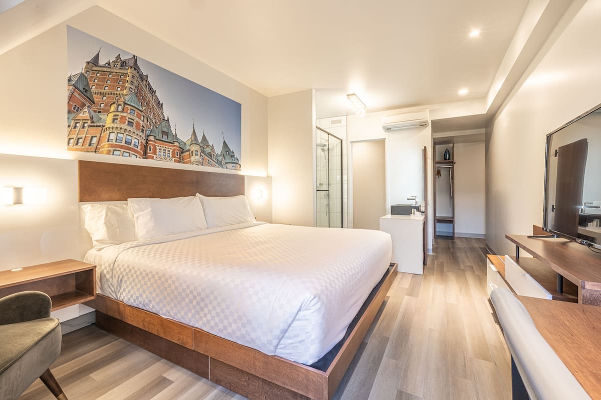 Ein modernes Hotelzimmer mit einem großen Bett, einem Schreibtisch, einem Stuhl und einem Fernseher.