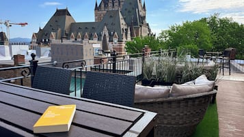A rooftop terrace with a view of a castle-like building, outdoor seating, and a book on a table.