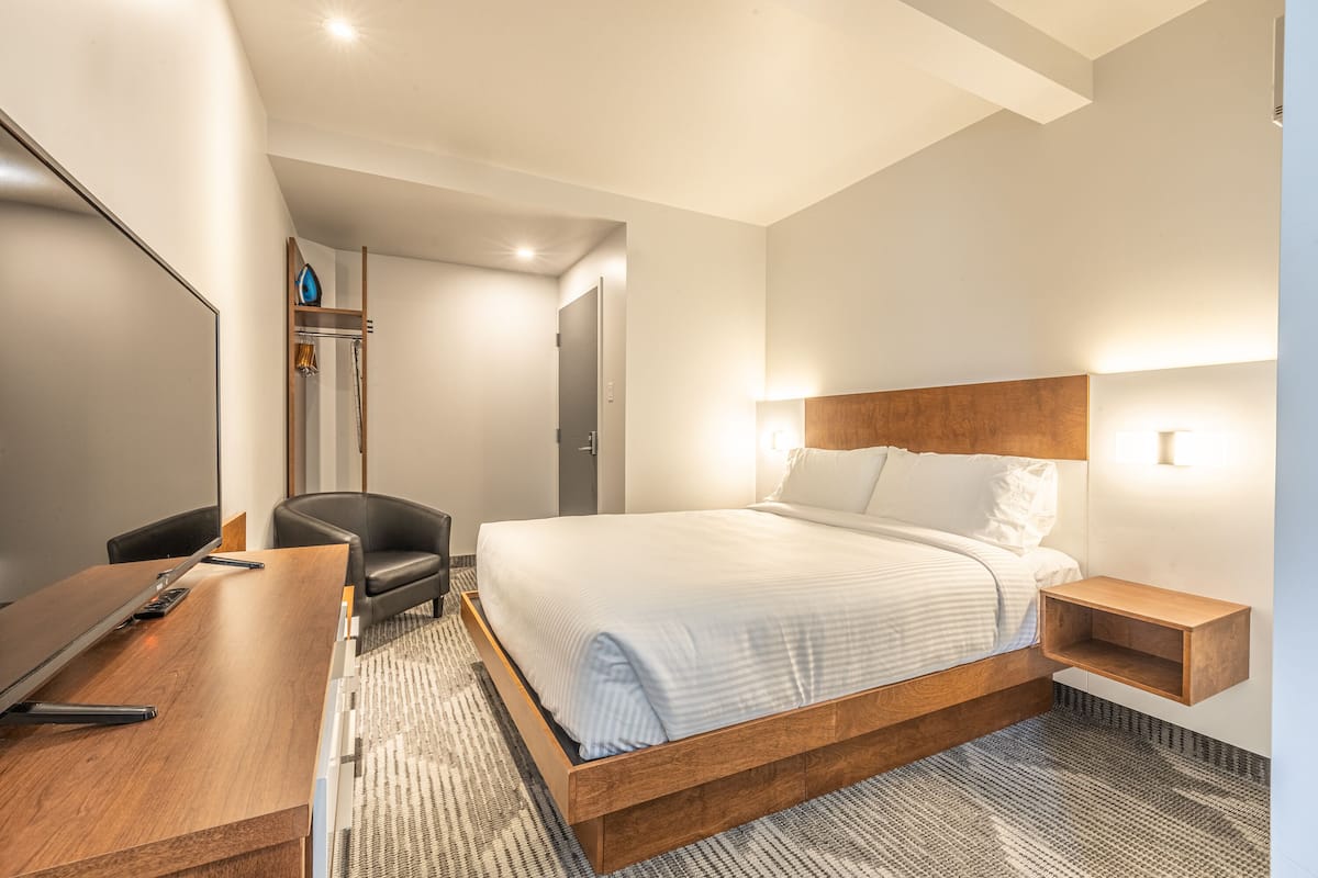 Ein modernes Hotelzimmer mit einem großen Bett, einem Schreibtisch und einem Stuhl.