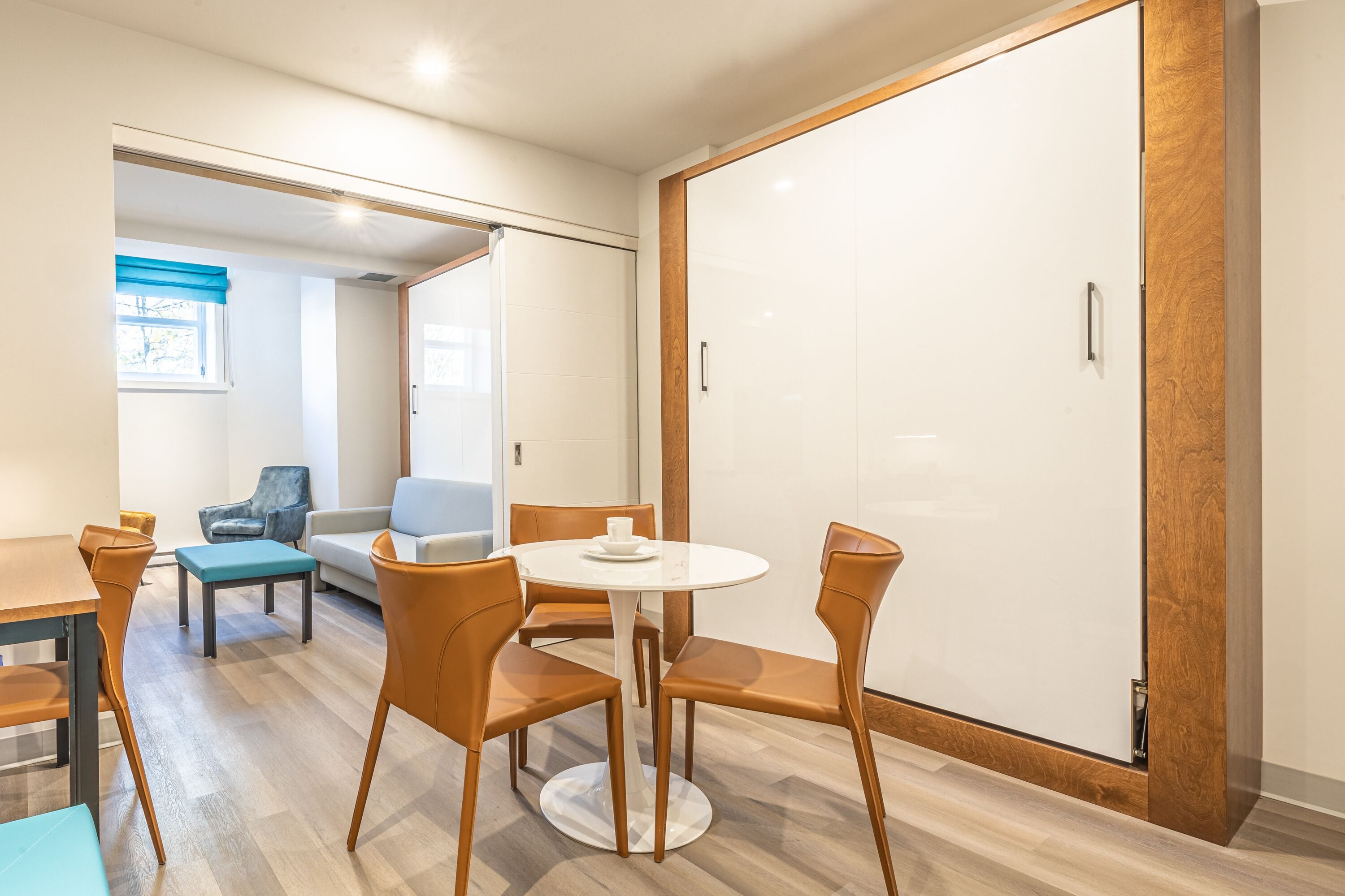A modern room with a round table and four chairs, a sofa, a small table, and a sliding door.