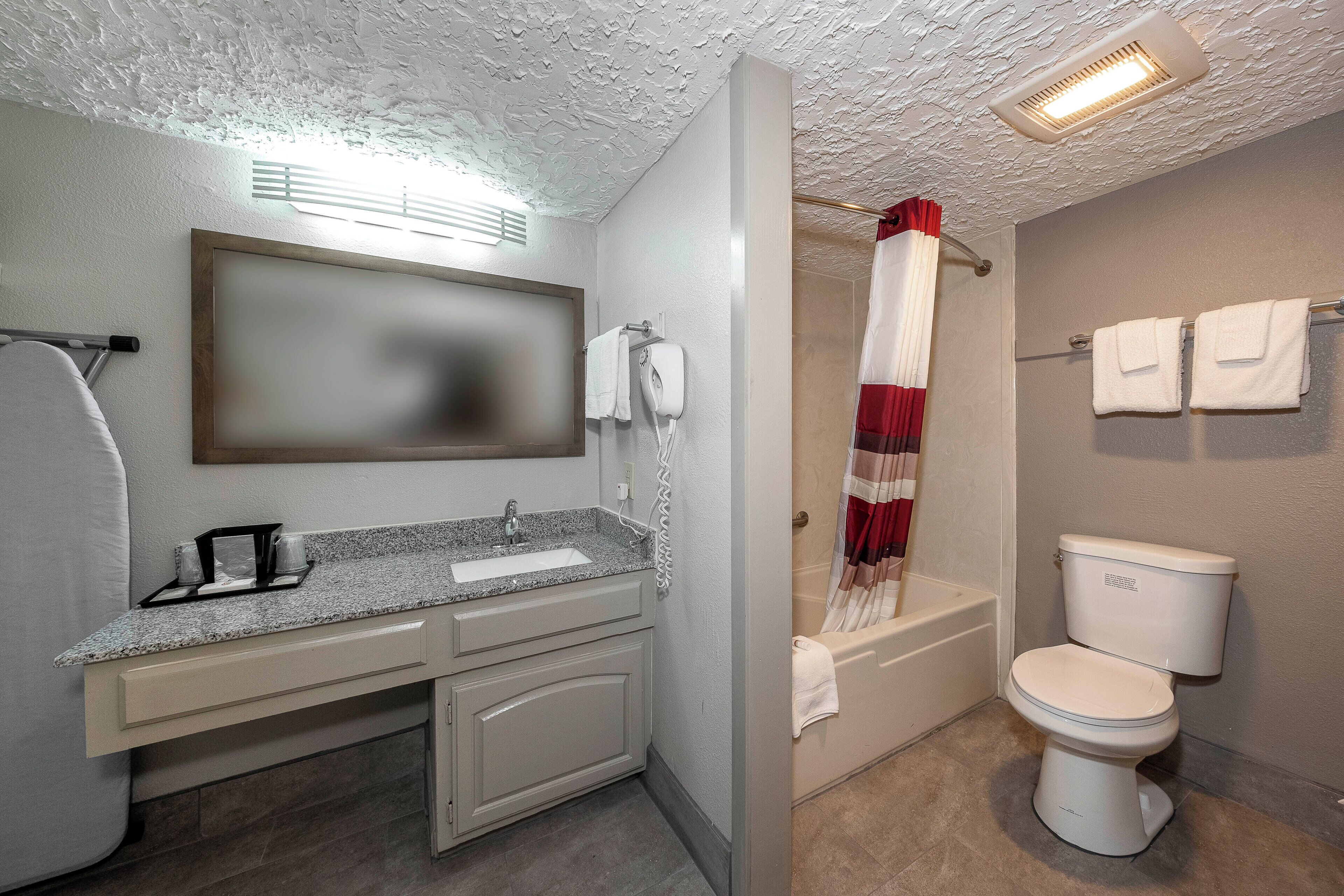 A bathroom with a sink, mirror, towel rack, shower curtain, and toilet.