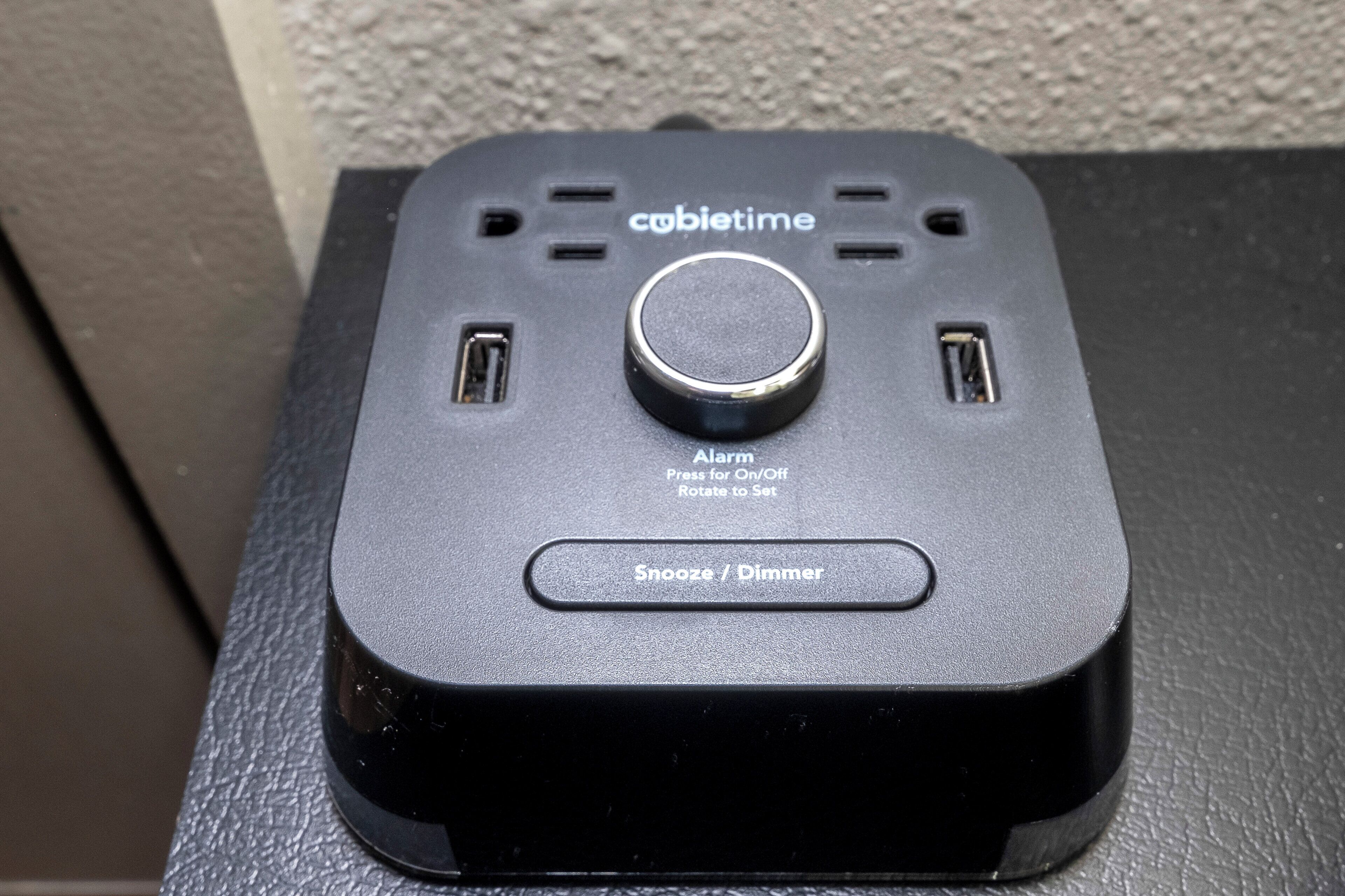 A black device with a central button and two side vents, labeled 'cabibtime' and 'Alarm' with instructions for use.