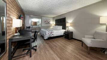A hotel room with a bed, desk, chair, and a small table.