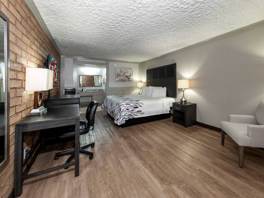 A hotel room with a bed, desk, chair, and a small table.