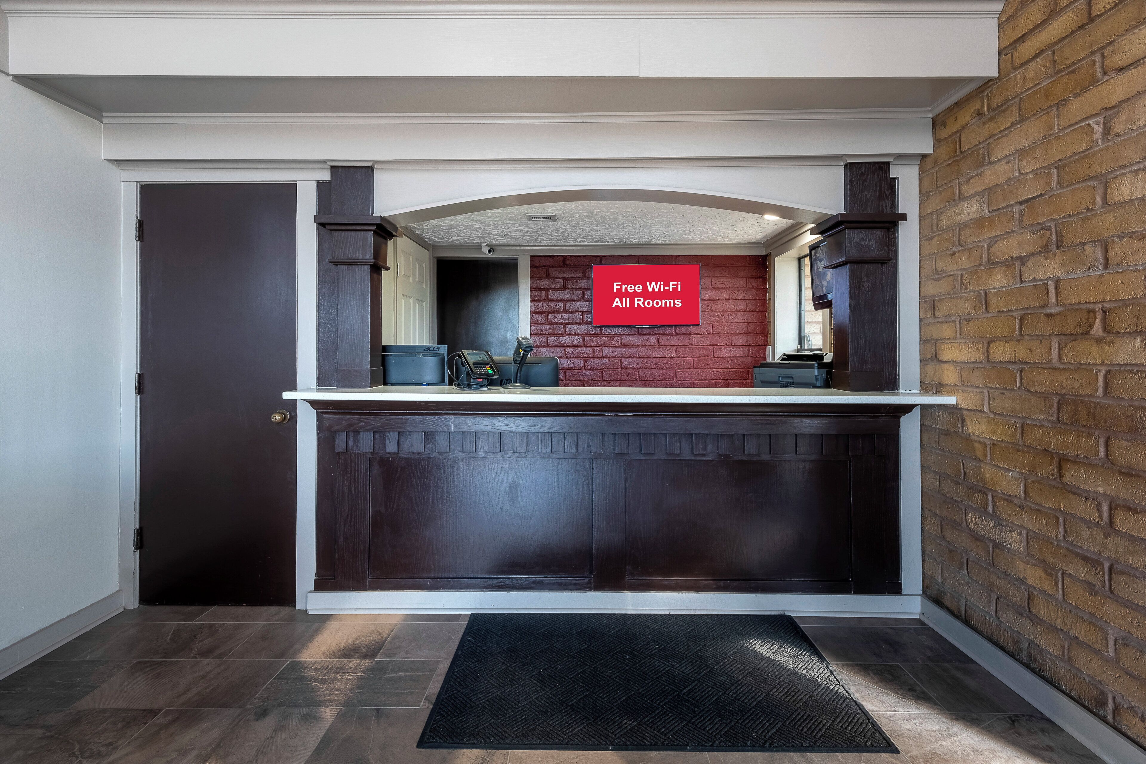 Una cocina moderna con un armario de madera oscura, una pared de acento de ladrillo rojo y un cartel que indica Wi-Fi gratuito en todas las habitaciones.