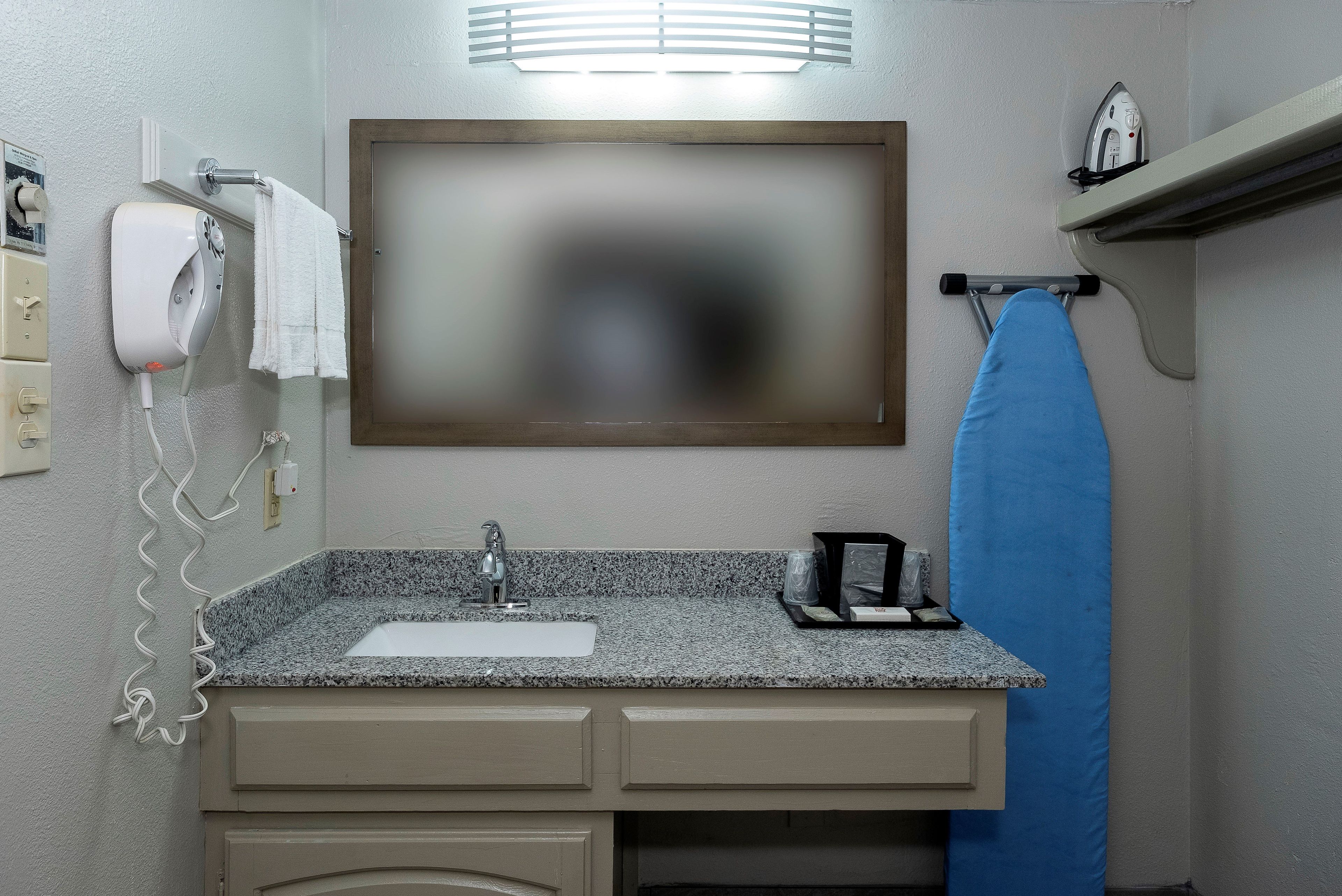 Un baño con lavamanos, espejo, toallero y secador de pelo.