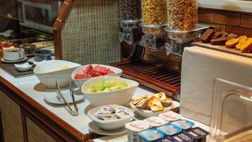 A buffet with various food items including bowls of fruits, cereals, and desserts.