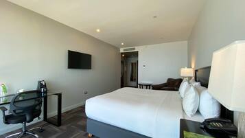 Habitación de hotel con una cama grande, un escritorio con silla, un televisor de pantalla plana, una lámpara y un teléfono.