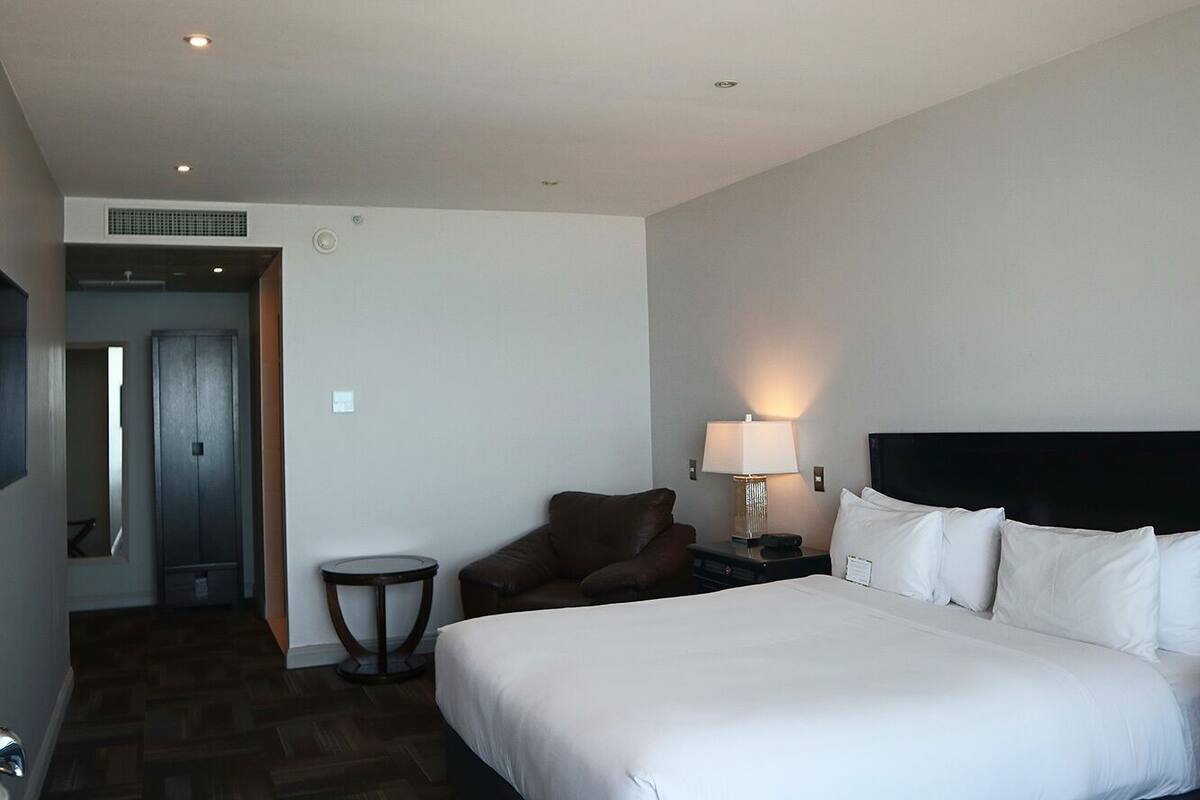 Une chambre d’hôtel avec un grand lit, une chaise, une petite table et une lampe.