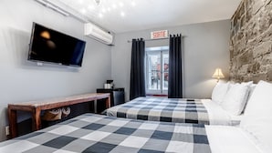 Habitación de hotel con dos camas, televisión, escritorio y vistas al exterior.