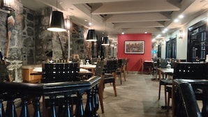 Un restaurante con paredes de piedra, muebles de madera e iluminación colgante.