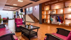 A hotel lobby with wicker furniture, a staircase, and a souvenir shop. - Hotel del Marquesado (Oaxaca)
