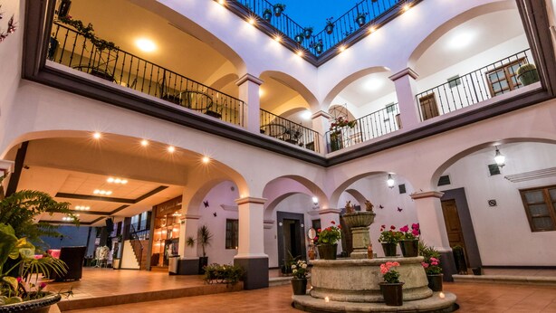 A multi-level atrium with arched ceilings, a central fountain, and potted plants. - Hotel del Marquesado (Oaxaca)