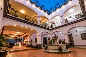 A multi-level atrium with arched ceilings, a central fountain, and potted plants. - Hotel del Marquesado (Oaxaca)