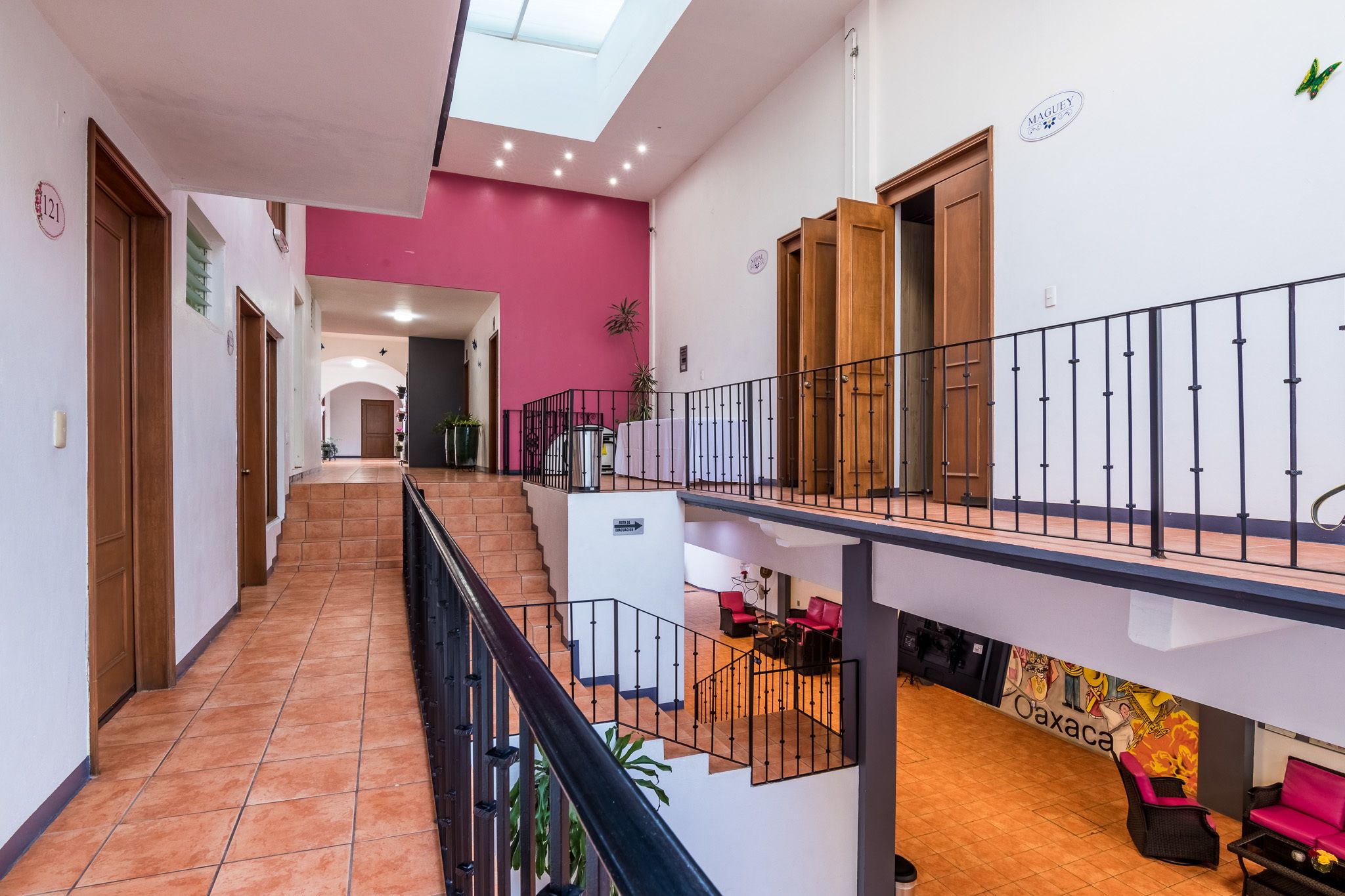 Un interior de varios niveles con una escalera, un balcón y zonas de estar.