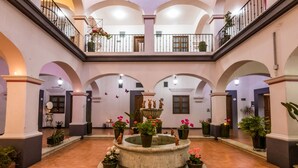 A spacious courtyard with a central fountain, multiple arches, and potted plants. - Hotel del Marquesado (Oaxaca)