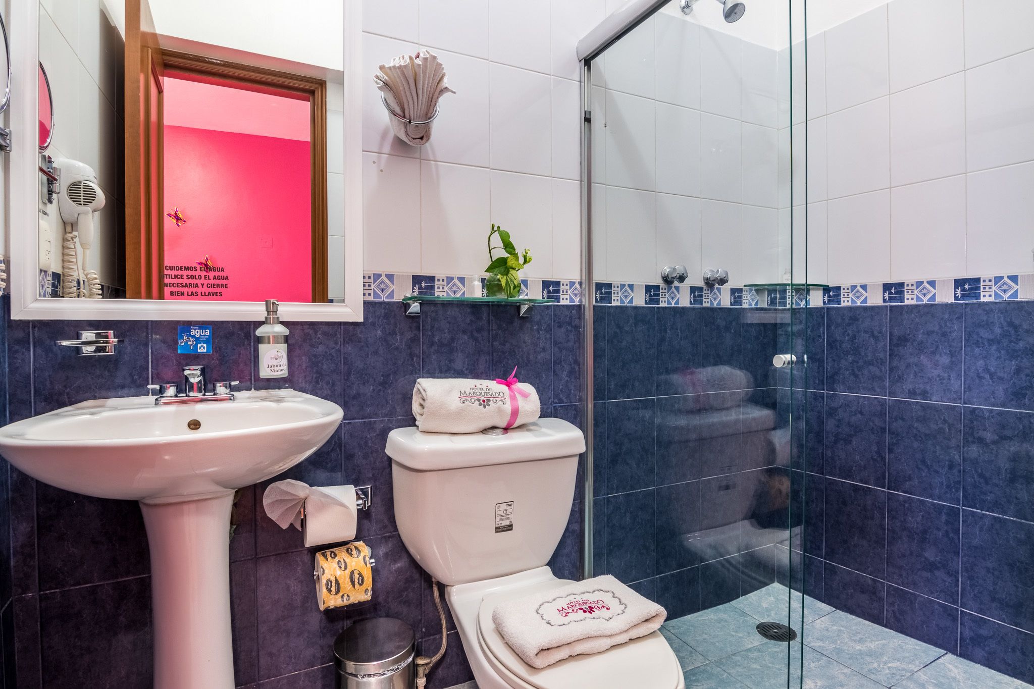 Et badeværelse med en hvid vask, toilet og en brusekabine i glas.