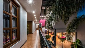 A corridor with a railing, potted plants, and a seating area with chairs and tables. - Hotel del Marquesado (Oaxaca)