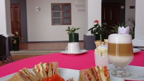 A table with sandwiches and a glass of milk, set against a white wall with arches and a door in the background. - Hotel del Marquesado (Oaxaca)