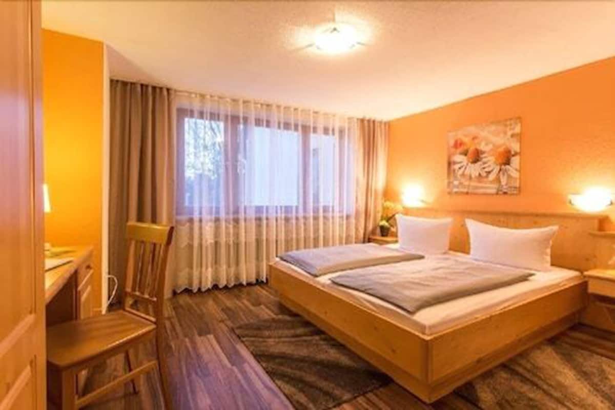 Habitación de hotel con cama de madera, un escritorio y una silla.
