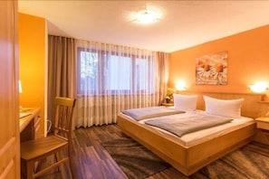 Ein Hotelzimmer mit einem hölzernen Bett, einem Schreibtisch und einem Stuhl.