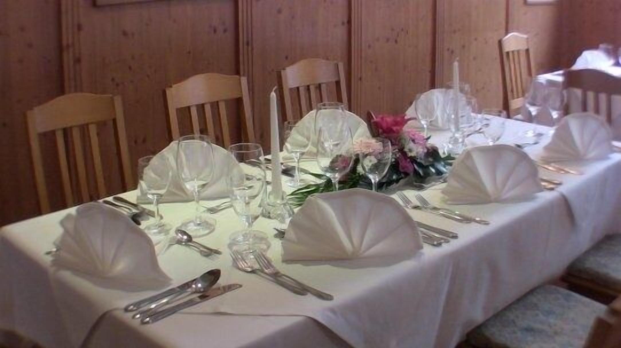 A table set for a formal dining event with white tablecloths, glassware, and floral centerpieces.