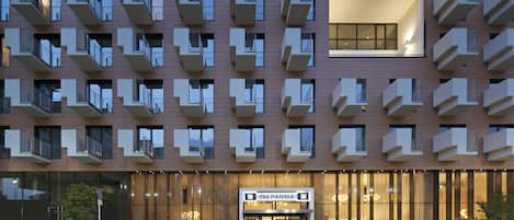 Un hôtel moderne doté de nombreux balcons, d’une entrée imposante et d’une enseigne indiquant « NH PARMA ».