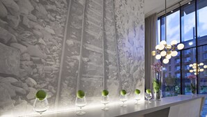 A bar area with a long counter, a stone wall backdrop, and a modern chandelier.