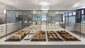 A modern kitchen with glass partitions, various baked goods, and a clean, organized layout.