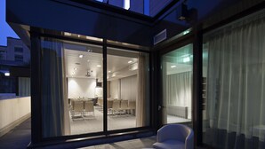 A modern hotel room with a glass door leading to a dining area.