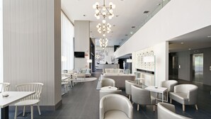 A modern hotel lobby with a mix of seating options, including tables and sofas, and a central reception area.