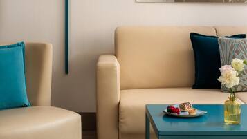 Un soggiorno moderno con un divano beige, un tavolino blu e un vaso con fiori.