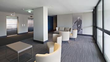 Un lobby moderno con una recepción, zona de estar, ascensores y un ventanal grande.