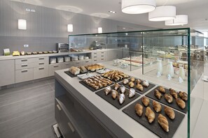 A modern breakfast buffet with a variety of pastries and baked goods displayed on black trays.