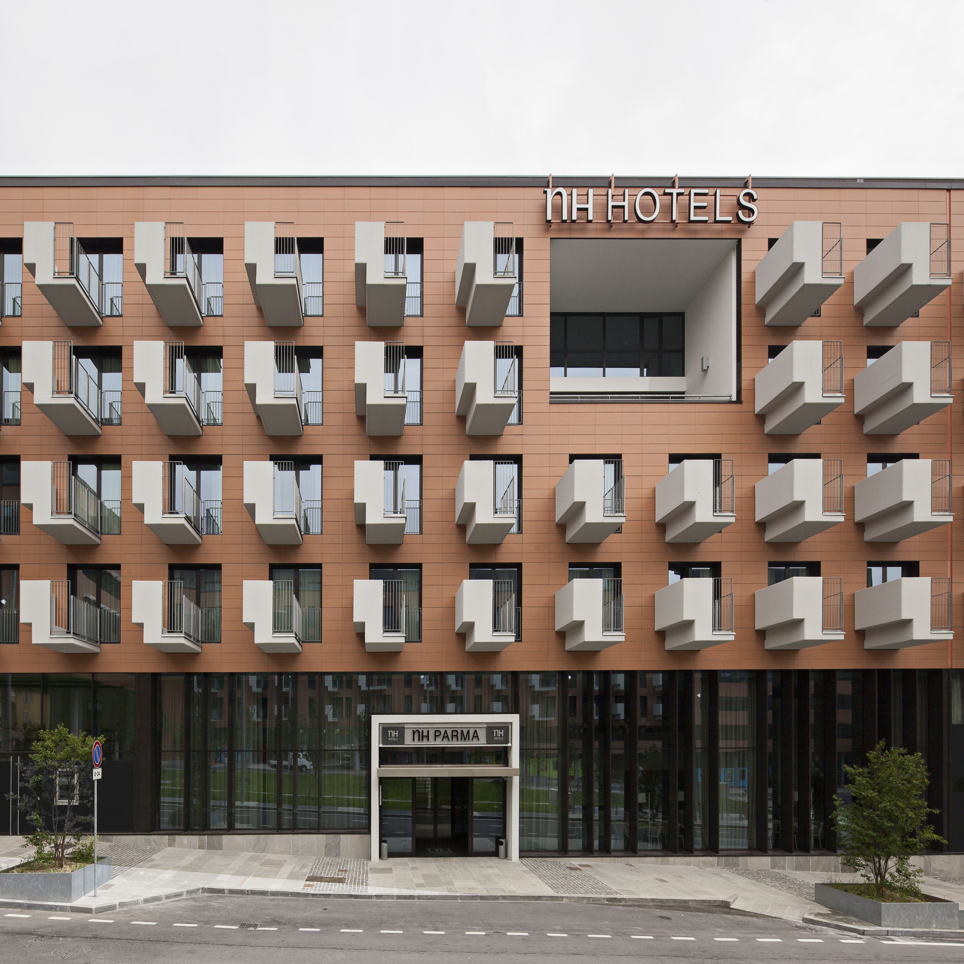 Un moderno edificio di un hotel con diversi balconi e un cartello con la scritta NH Hotels.