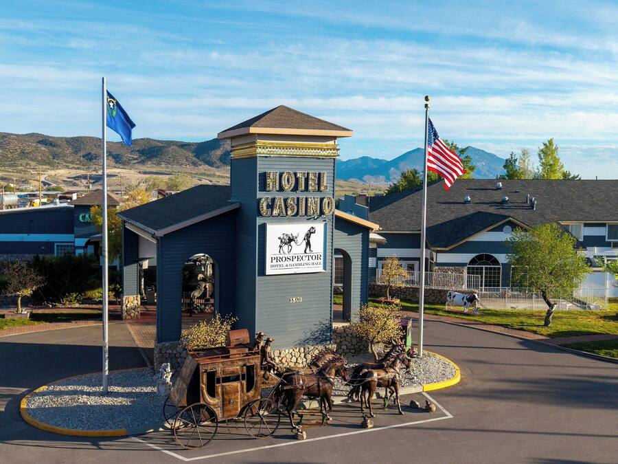 A hotel with a prominent sign, two flags, and a horse-drawn carriage in the foreground.