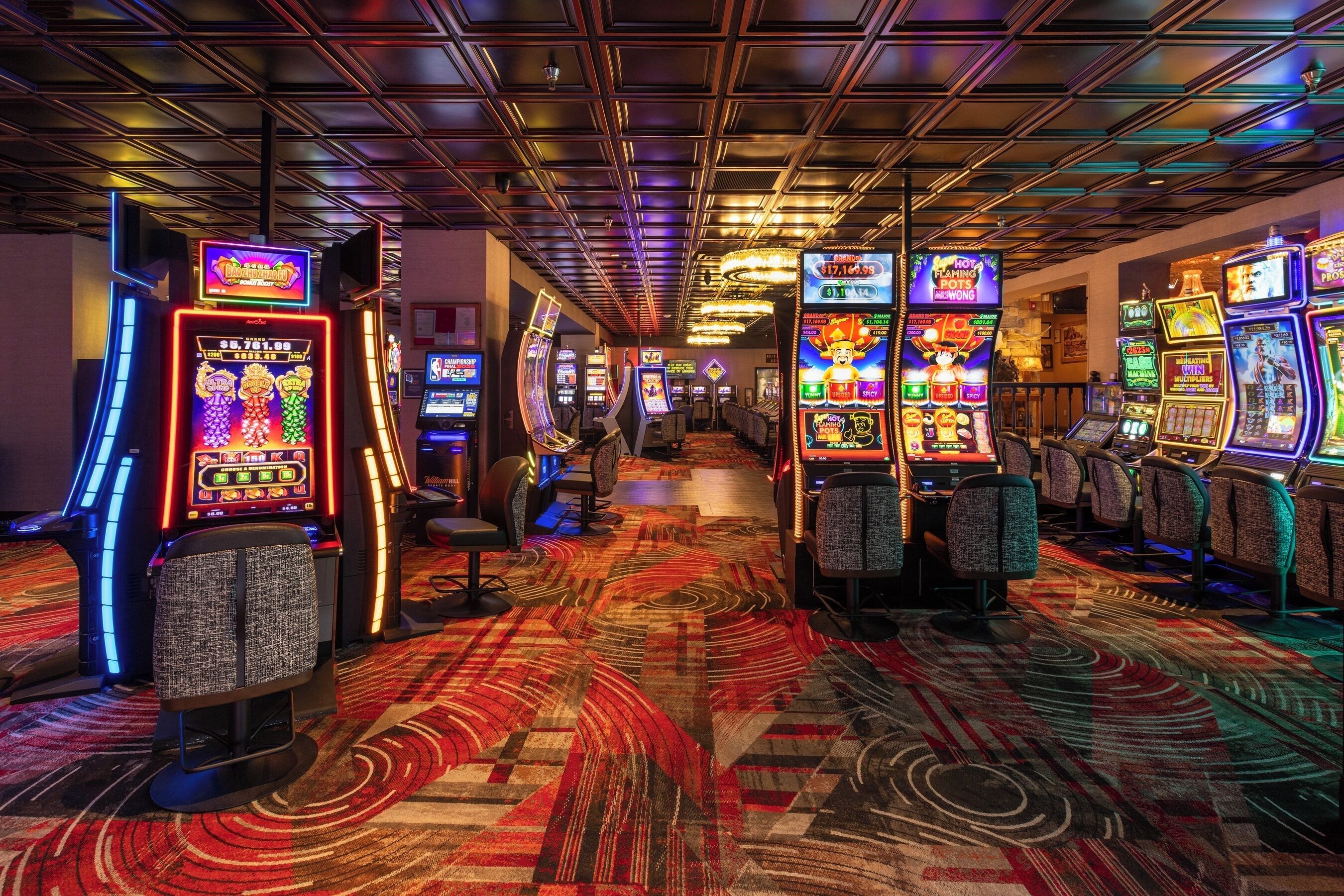 Une salle de casino avec des machines à sous et un tapis recouvrant le sol.