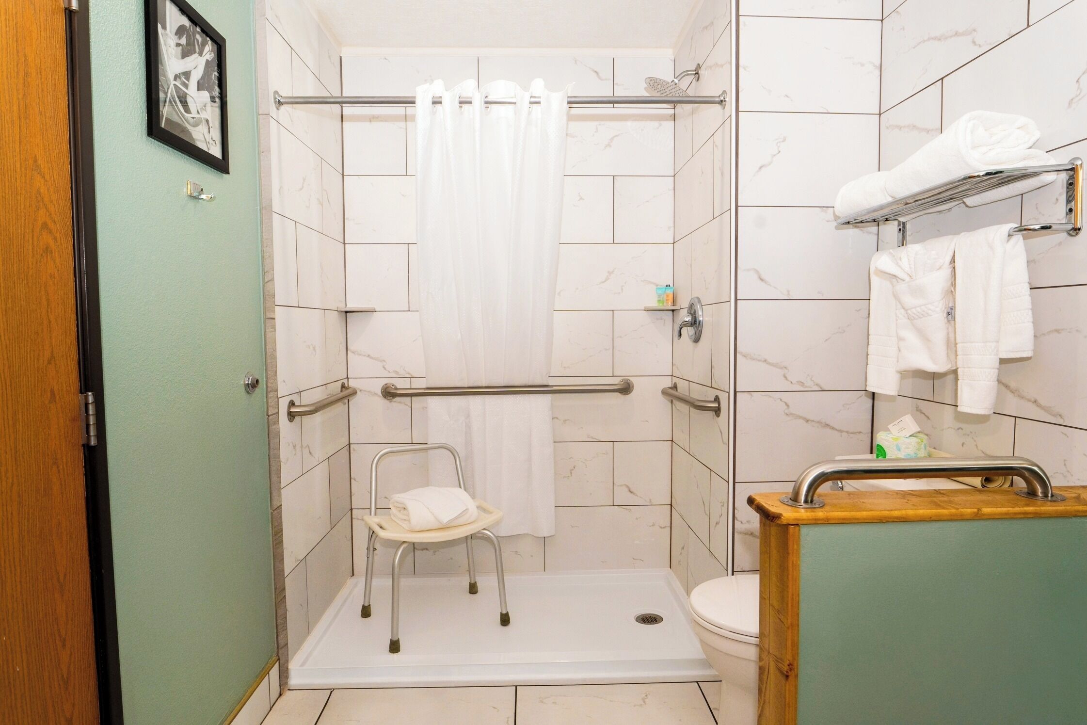 Ein Badezimmer mit Dusche, Toilette und einem kleinen Stuhl.