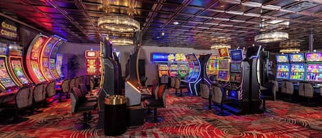 A casino with multiple slot machines, gaming tables, and a patterned carpet.