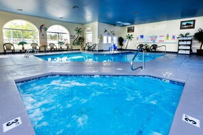 An indoor swimming pool with multiple lanes, safety signs, and lounge chairs. - Prospector Hotel & Gambling Hall (Ely)