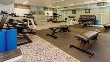 A gym with exercise equipment, a mirrored wall, and a patterned floor.