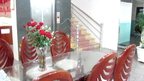 A hotel lobby with a glass-top table, red chairs, and a vase with red flowers. - Thanh Hong Hotel (Ho Chi Minh City)