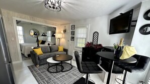 Un salon moderne avec un canapé, une table basse et un coin bar équipé de tabourets.