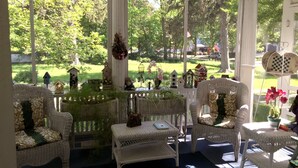 Une véranda meublée de mobilier en osier, avec vue sur un jardin verdoyant et agrémentée de nichoirs.